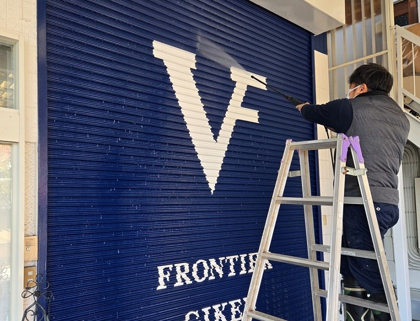 シャッターの汚れを豪快に落とす三浦チーフ